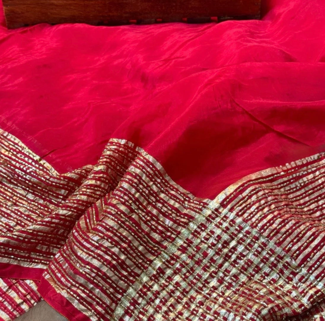 Red fabric with gold and silver embroidery on a wooden surface