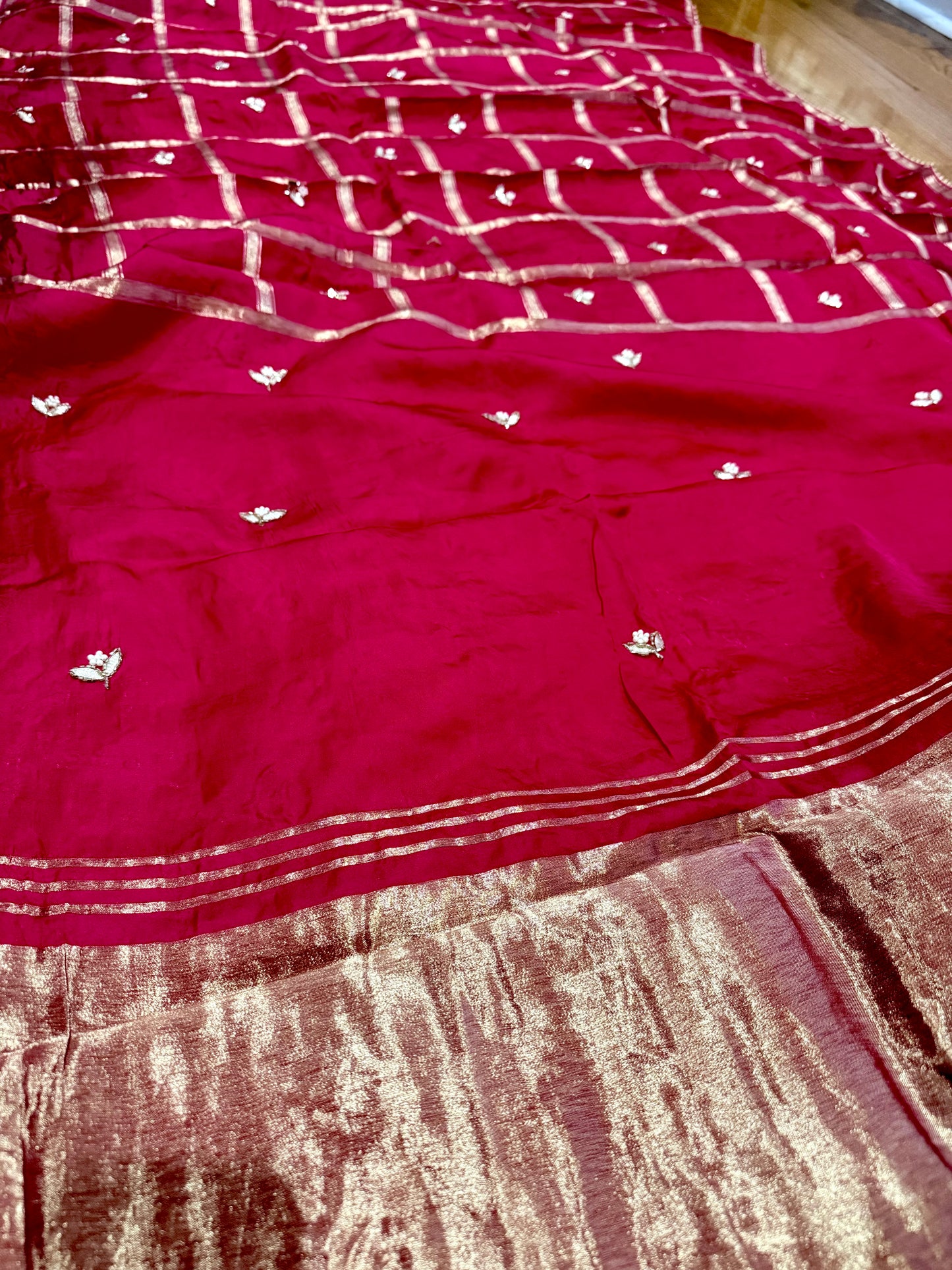 Red saree with white patterns on a wooden surface