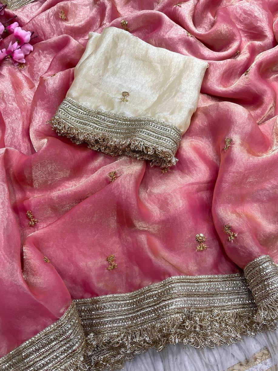 Pink saree with white blouse and gold embroidery on a pink fabric background