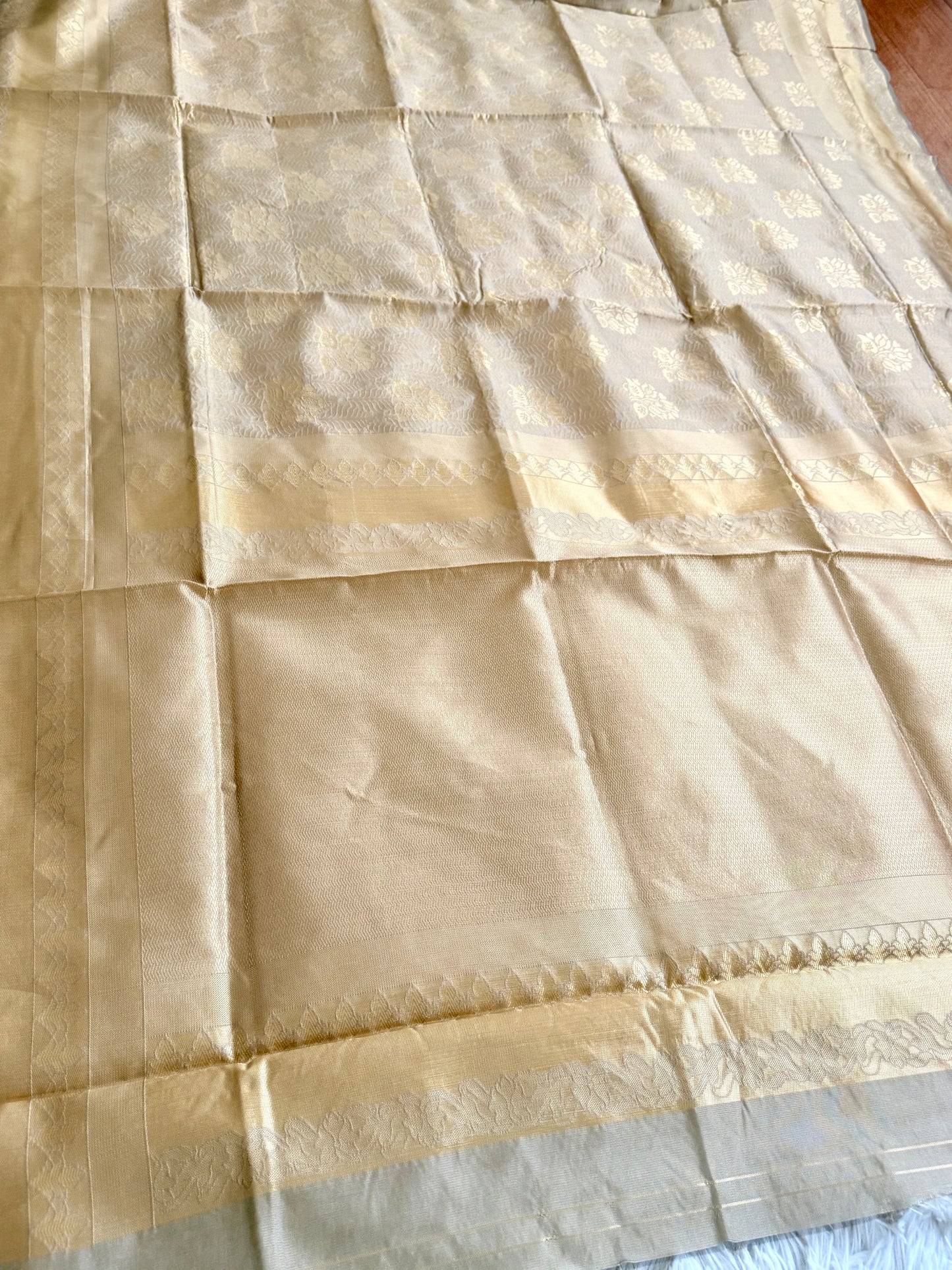 Beige fabric with a subtle pattern, possibly a sari or a similar type of textile.