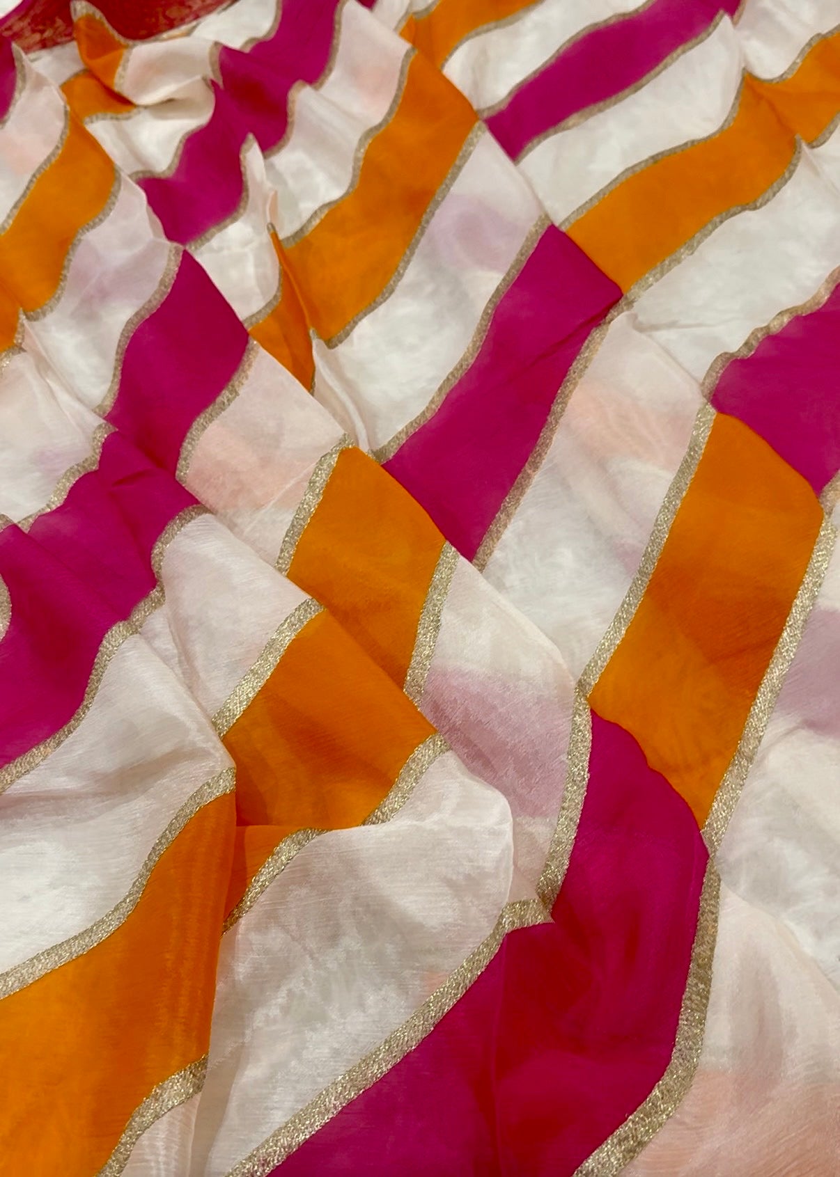 Close-up of a fabric with wavy pattern in pink, orange, and white.