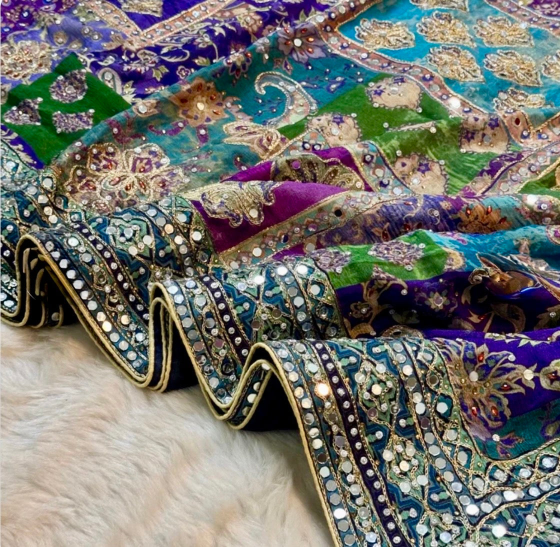 Close-up of intricately designed fabric with embroidery and sequins on a textured surface.