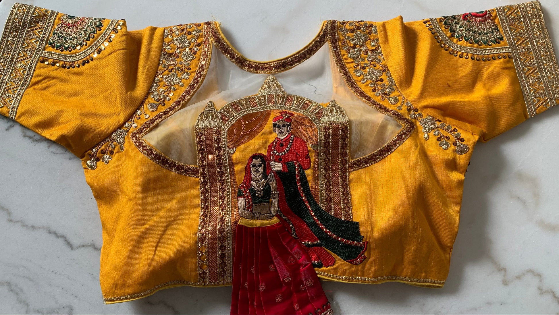 Yellow embroidered blouse with intricate designs on a marble surface