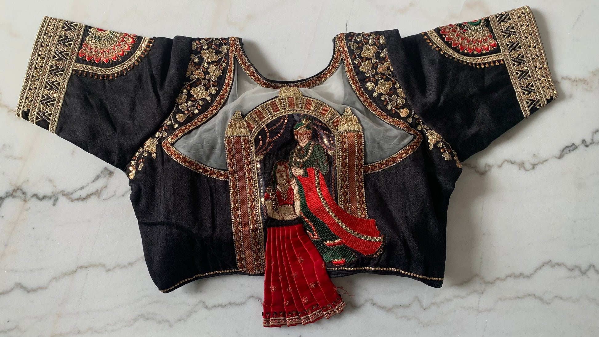 Traditional embroidered blouse with intricate designs on a marble surface